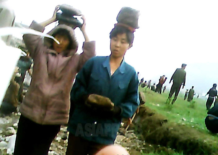 河川敷の整備に動員され石を運ばされる女性たち。2013年6月、北部地域にて撮影「ミンドゥルレ」(アジアプレス)