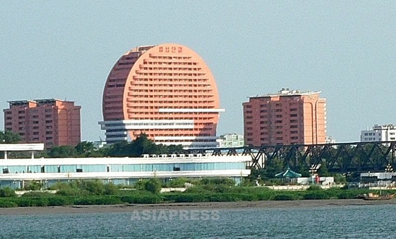 中国側からも目を引く円形のビル。上部には「一心団結」のスローガン。右下の鉄橋は中国と結ばれる国際連絡橋だ。新義州市。