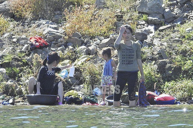2019年9月に撮影した写真。鴨緑江で洗濯する女性たち。夏場は水浴びする人も多かったが、現在はこのような姿はまったく見えない。中国側から石丸次郎撮影。