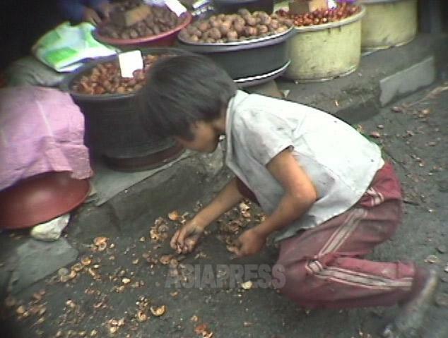 目の前にある食品を買えなくて拾い食いする少女。1998年10月に元山で撮影アン・チョル（アジアプレス）