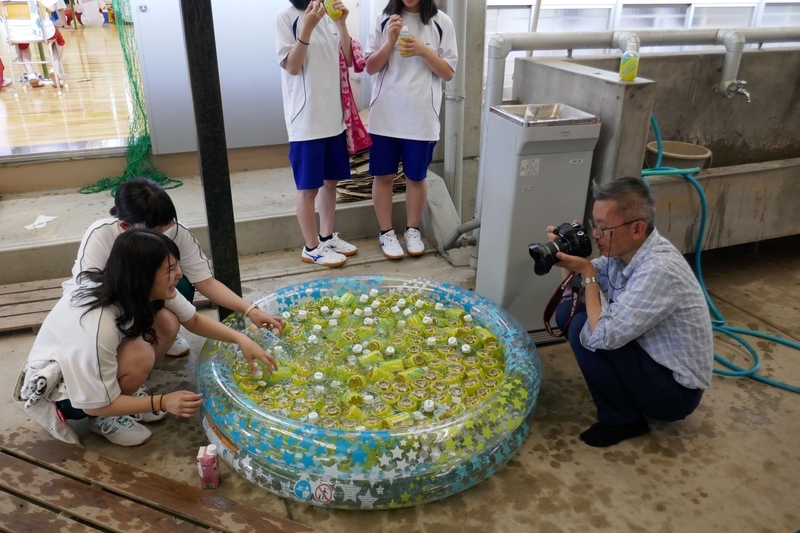 クラスマッチ（スポーツイベント）の休憩で飲み物を選ぶ生徒を撮影する堤教諭。生徒も写真撮影に慣れている（筆者撮影）