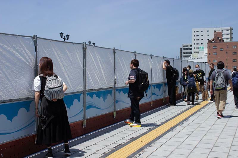 相生橋の南側。シールドの隙間から平和記念公園を覗き込む観光客らしき人たち／筆者撮影