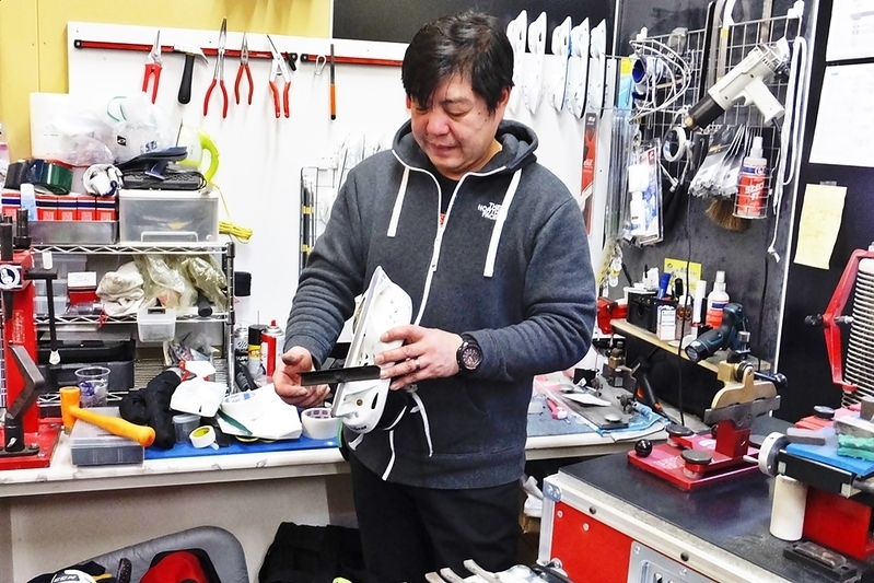 多くの用具が置かれている仕事場で選手のスケートを手入れする (Rights of Jiro Kato)