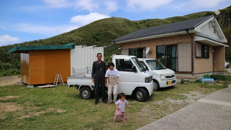 村営住宅と秀成さんがDIYでつくった作業小屋の前で。鎌倉秀成さん（38）、今日子さん（33）夫妻と長男の帆汰（ハンタ）くん