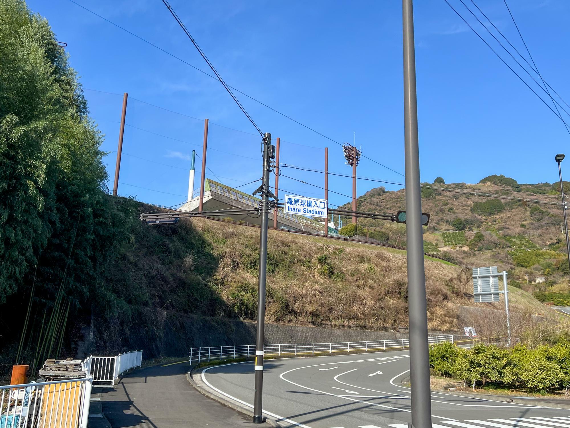バスを降りて１００メートルほど歩いて交差点を左折すると、高台にある球場のスタンドと照明塔が見えてくる
