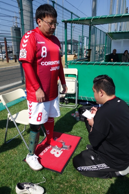 アンプティサッカー選手の片足のサイズを測るニューバランス社員の下田和希氏（筆者撮影）