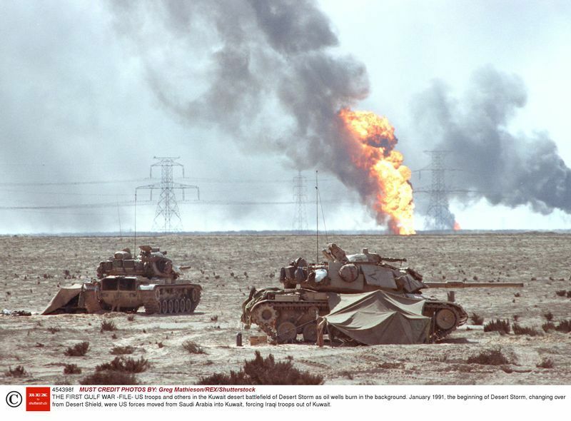 1991年、クウェートの砂漠の戦場に配置された、米軍戦車。燃える油田が背景に見える。