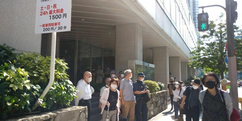 通常通りの利用が行われている「エル・おおさか」（大阪市中央区）の向かいでは、日の丸を掲げたグループが「表現の不自由展」に抗議活動。警備にあたる警察官が出動していた＝2021年７月11日、筆者撮影