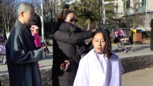 髪を剃って抗議する原珊珊。拘束された弁護士、謝燕益の妻。左は李文足（2018年12月　北京）