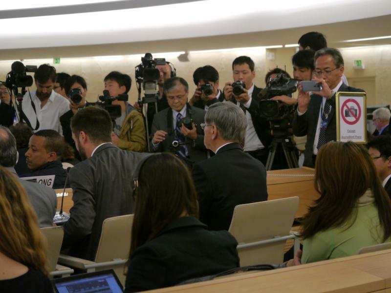 大勢の記者に囲まれる中、国連人権理事会で口頭声明を発表する翁長雄志さん（中央）（阿部藹さん撮影）