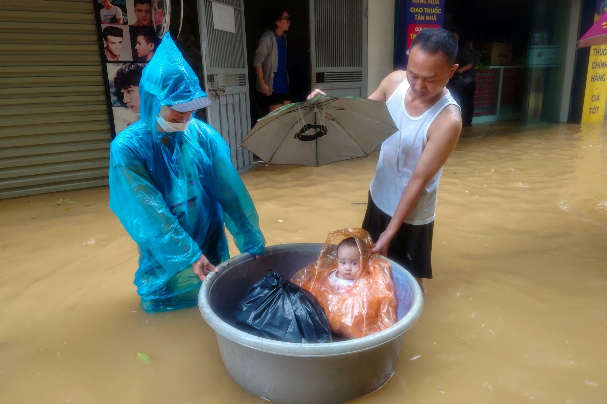 台風11号により洪水が起きたベトナム・ハノイで、タライに乗って救助される幼子 (11日)