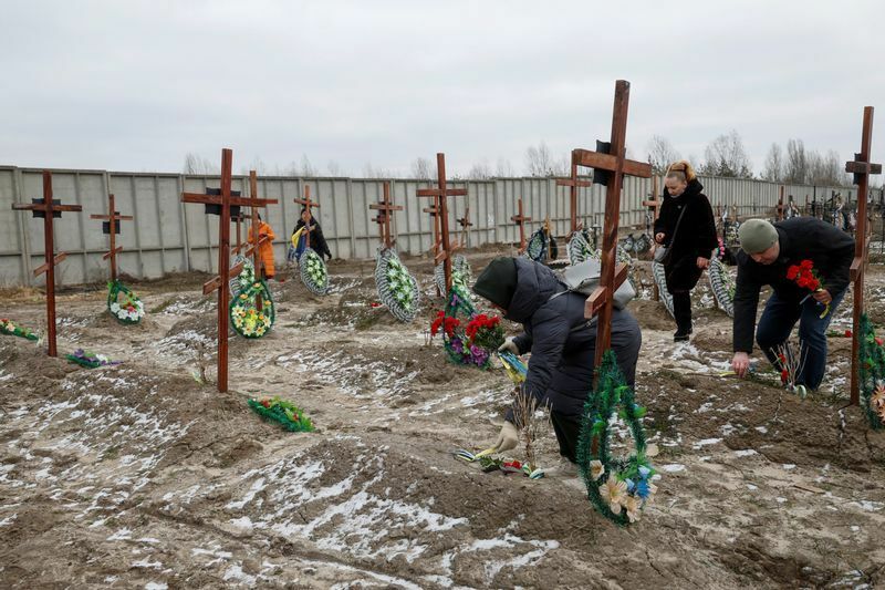 ウクライナ侵攻開始から1年の節目にブチャの墓に花を捧げる人々（2023.2.24）。ブチャで多くの民間人の遺体が発見されたことは、ロシアの戦争犯罪への批判を高めるきっかけになった。
