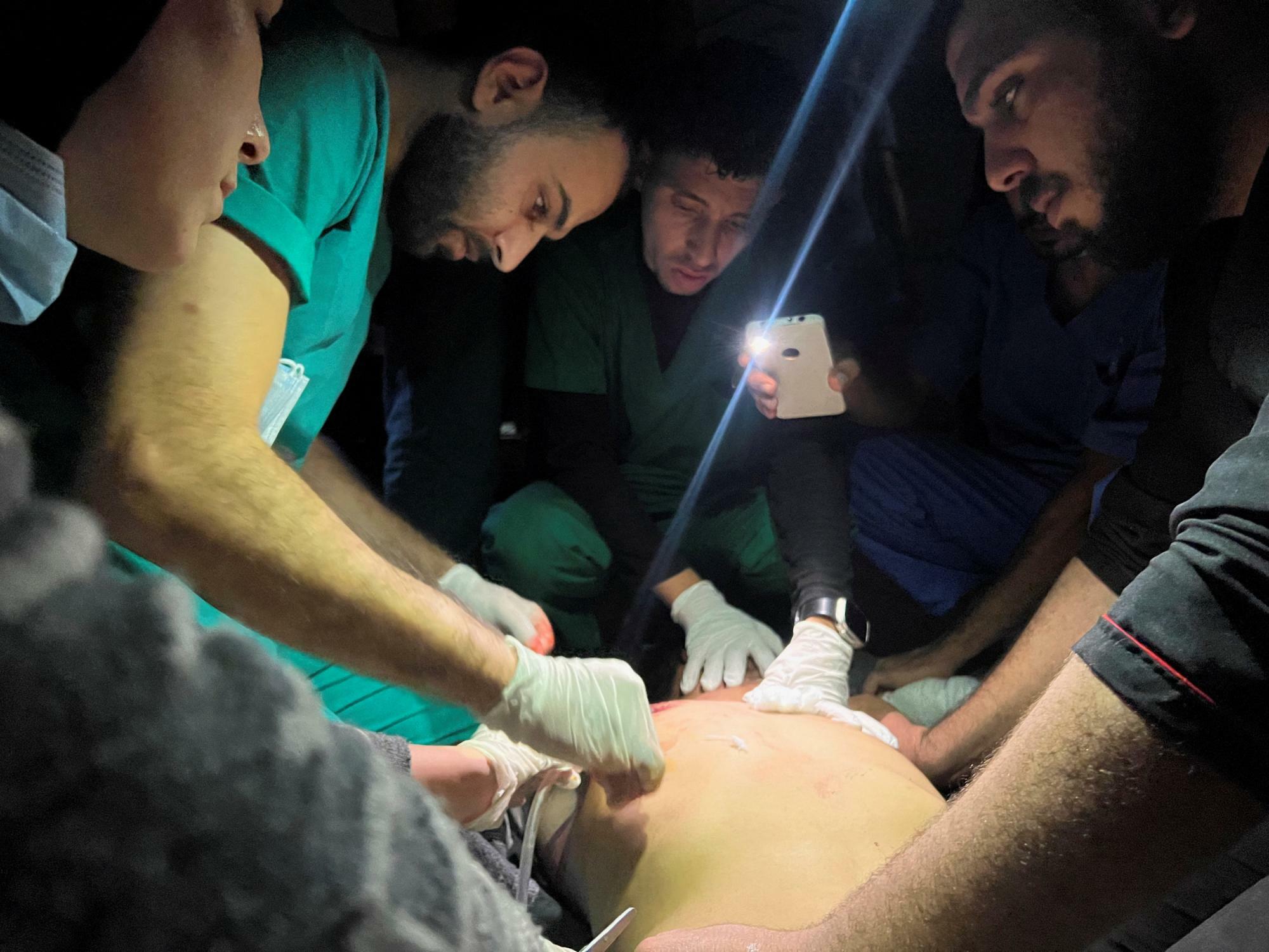 イスラエル軍の空爆によって破壊されたガザの病院でスマートフォンの明かりを頼りに怪我人の処置をする医師（2023.11.16）。イスラエルによるガザ侵攻では既に1万人以上の死者が出たとみられる。