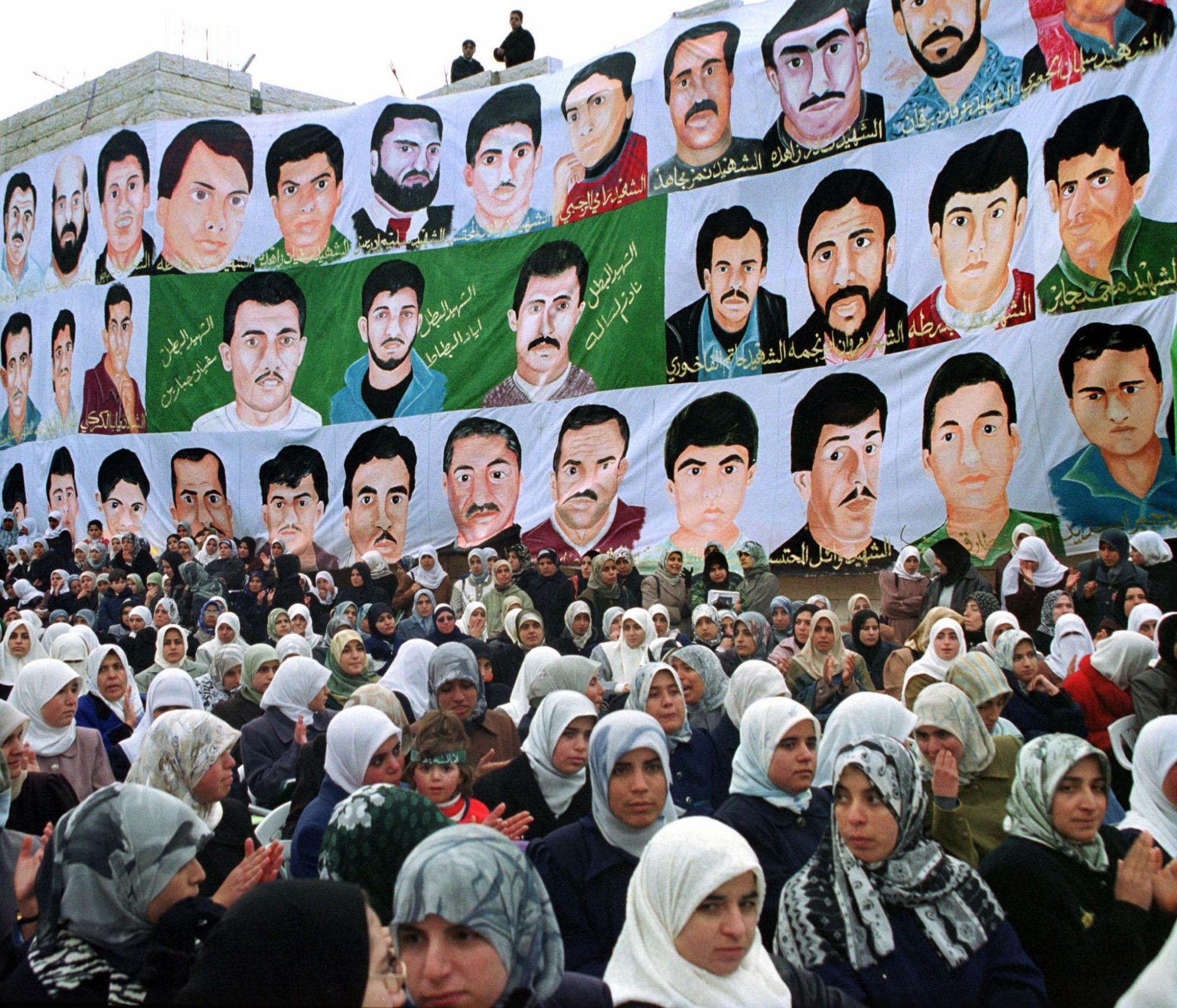 イスラエルへの抵抗運動「インティファーダ」で殺害された夫や父親の肖像画を掲げるパレスチナ人女性（2000.12.11）。自然発生的だったインティファーダを統率して台頭したのがハマスである。