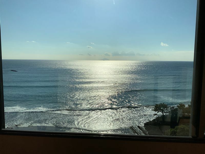 対局場は静岡県今井浜にある旅館「今井荘」。対局室は最上階にあります。封じ手部屋（対局室内の隣の部屋）からは今井浜の海が一望できます。朝日に照らされている情景。