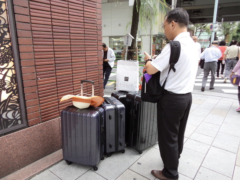 真新しいスーツケースの番をする男性