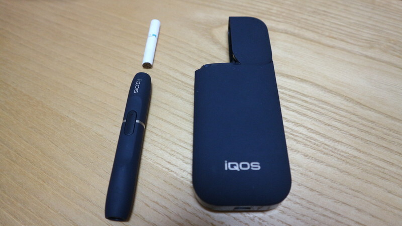 iQOS 左のペンシル型のものに上の白いタバコを刺し吸う。右は充電器。