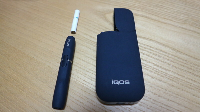 iQOS 左のペンシル型のものに上の白いタバコを刺し吸う。右は充電器。
