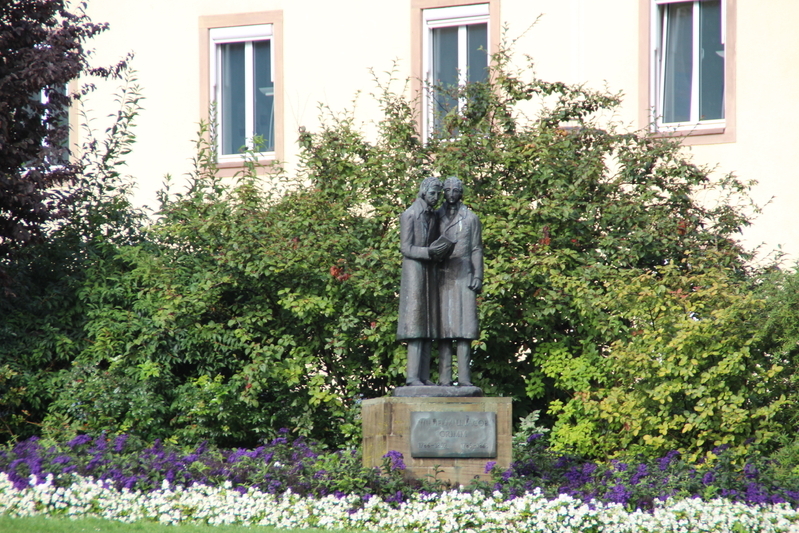 メインストリート・オーベレ・ケーニヒス通りとヴィルへルムスへーアー・アレーとが交差している地点のグリム兄弟広場にたつ銅像（筆者撮影）