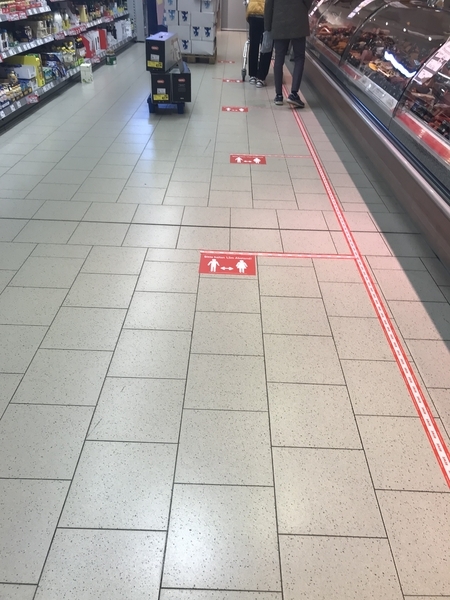 スーパー店内でも接触制限を厳守。他の客と少なくとも1.5メートルの距離を置くラインが床に貼られている。自宅近くにて4月1日撮影（ｃ）norikospitznagel