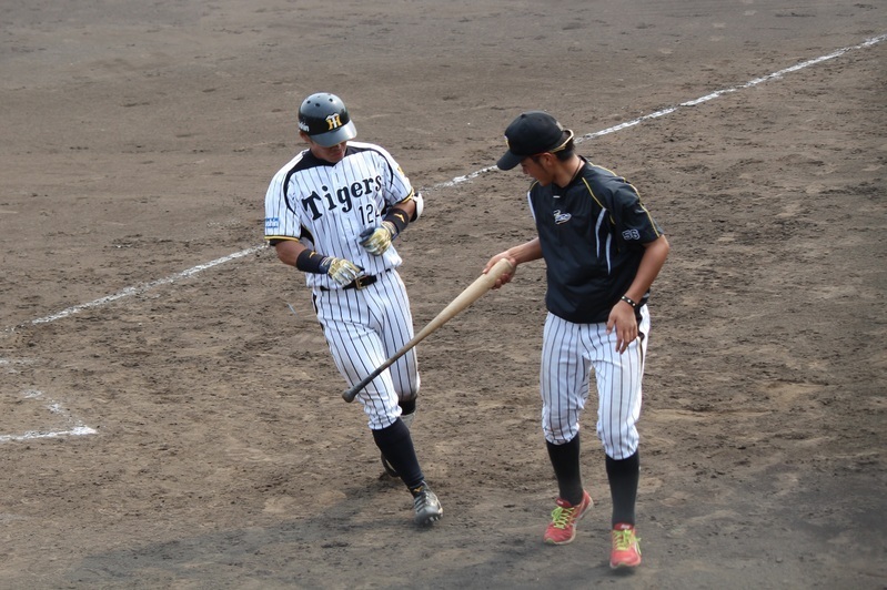 松田投手(右)から打ったバットを手渡される原口選手。ホームランなんだけどね……