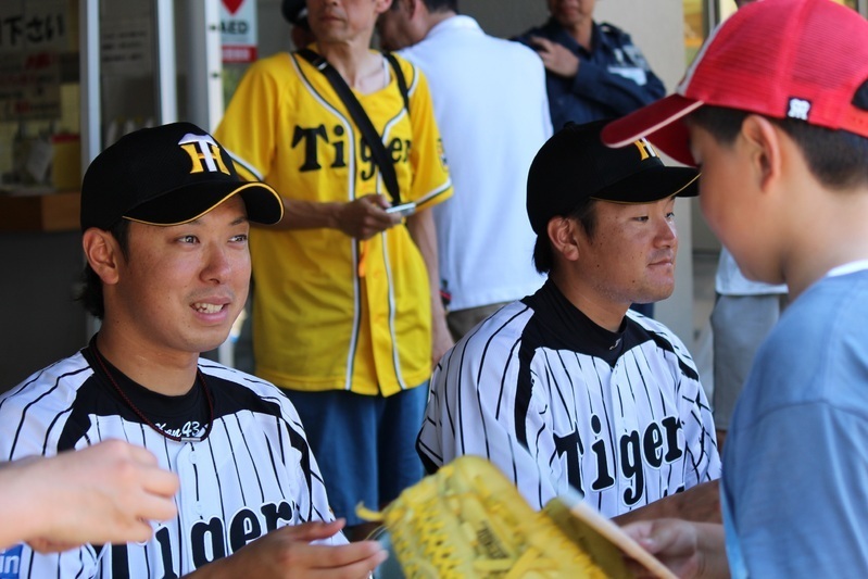 試合前のサイン会。にこやかに色紙を手渡す西村投手(左)と27日に先発する鶴投手。