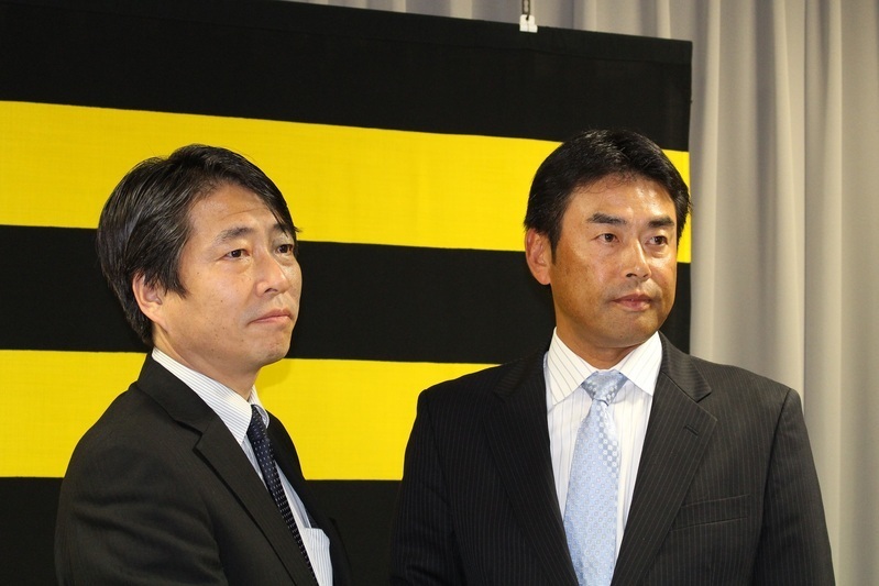 就任記者会見で高野球団本部長(左)と握手をする香田コーチ。