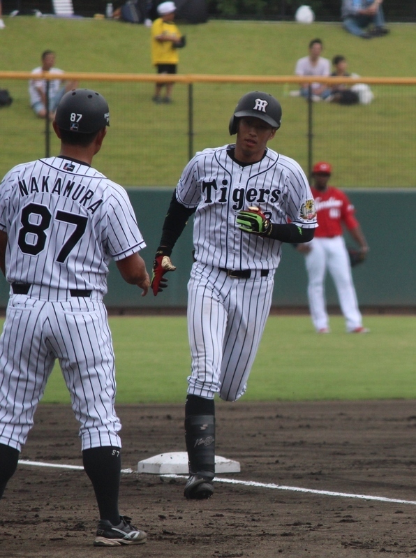ホームランを打って三塁を回る西田選手(右)。迎える中村コーチ。