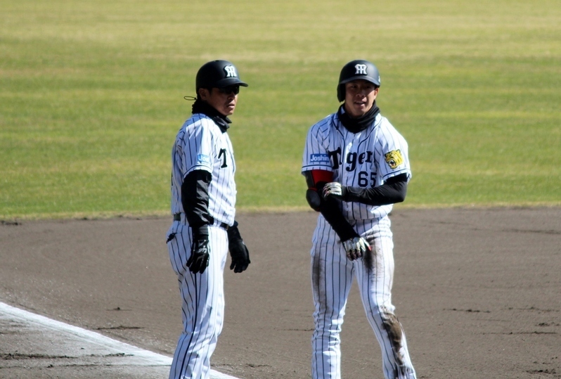 三塁で藤本コーチと笑顔を交わす緒方選手。