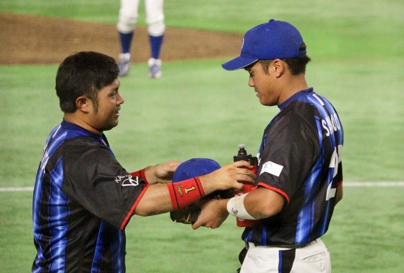 戻ってきた柳田選手(左)にグラブと水を渡す阪口選手。