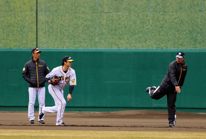 矢野監督(左)に見守られながら、相澤さん(右)に送球動作を教わる横田選手(中)。