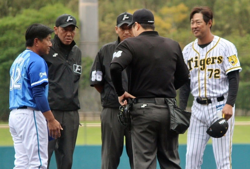試合開始前のメンバー表交換を行う阪神・高橋監督代行(右)と、DeNA・万永監督(左)。