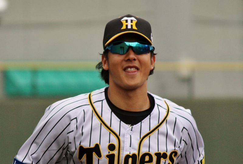4月の鳴尾浜、試合中に外野手とのキャッチボールから戻る横田選手。カメラに気づいて笑みが広がります。