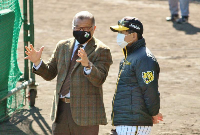 2月16日に安芸を訪問した阪神レジェンドテラー・掛布氏(左)と、打撃練習を見ながら話す平田監督(右)。