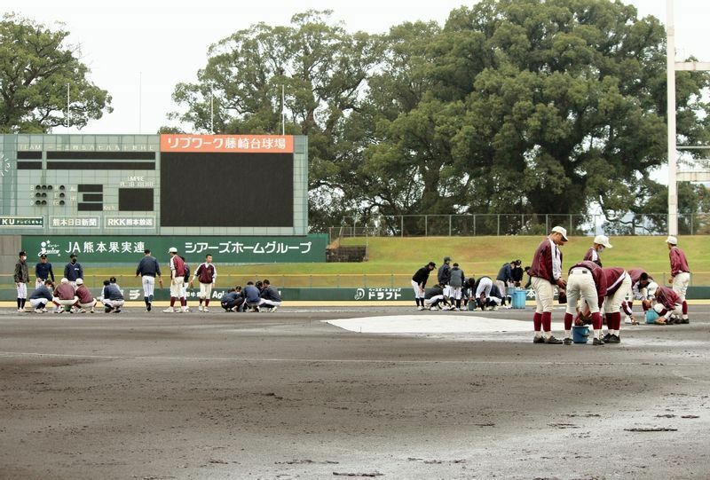 第2試合に向けて、グラウンドの水取り作業中。えんじ色が済々黌、紺色が熊本学園大付属の選手たちです。