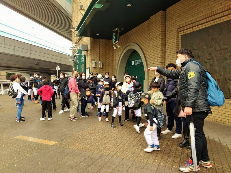 ちょうど雨も上がって、集合場所である阪神甲子園球場８号門前に集まるタイガースアカデミー岡山校の皆さん。森田コーチ(右端)が、保護者の方も来てくださいと呼びかけています。