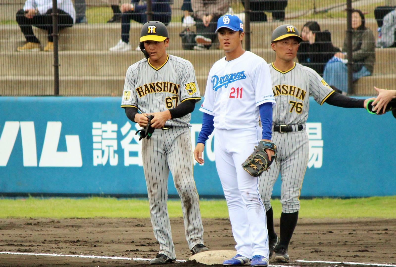 5回からファーストを守った板山選手(中)。6回表、阪神・高寺望夢選手(左)が中前打で出塁したところで、右は阪神・工藤隆人コーチです。