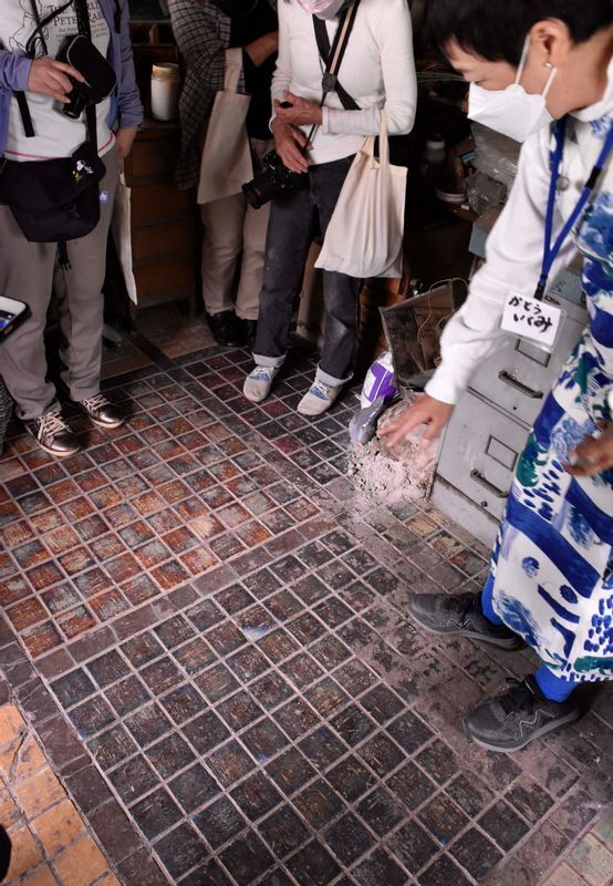 見学会の参加者を案内する加藤さん。見本室は3室あり、部屋ごとに様々なタイプのタイルが床や壁に貼り付けられていた