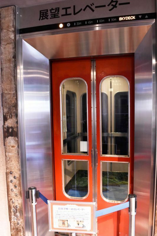 3階から展望デッキへ上がるエレベーターのうち一基は、1972（昭和47）年製。エレベーターガールが同乗し手動で扉を開閉する。現役で稼働しているのは日本唯一でこれもまた昭和の文化遺産といえる