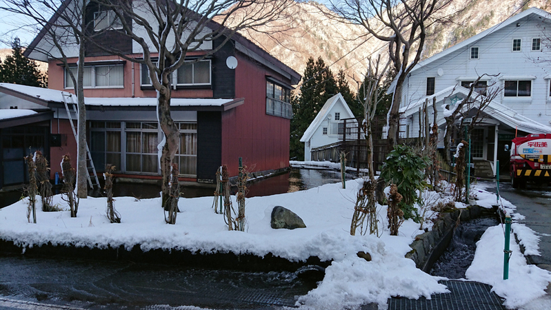 図1 雪国の用水路と家屋の位置関係。庭のすぐ先に雪が排除できる水路がある。屋根の雪も水で消す工夫も見られる（29日16：45追加、新潟県湯沢町にて、筆者撮影）