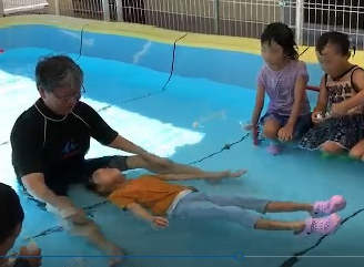 図2 保育園のプールで子供たちにういてまての指導をしている木村隆彦氏（左側　木村氏提供）