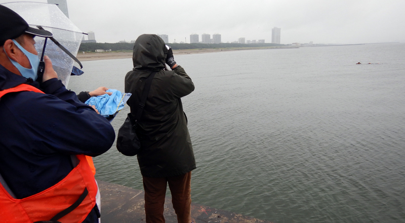 図3 深浅測量の様子。陸上調査員が距離を測定して、沖の海面調査員を測定点に誘導し、深さの測定を行う（筆者撮影）