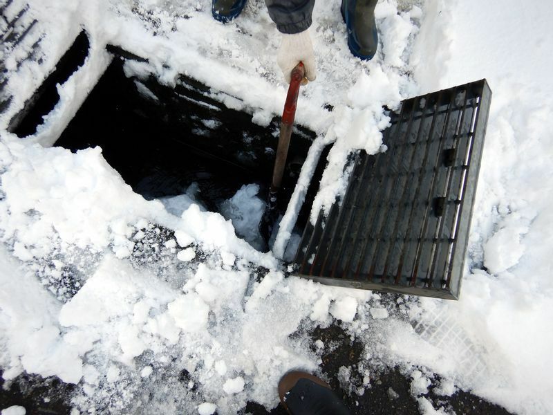 図3 流雪溝の雪捨て口を開いて溝にたまった雪をスコップで崩している。男性によると今年のこの溝の流れはあまり良くない（筆者撮影）