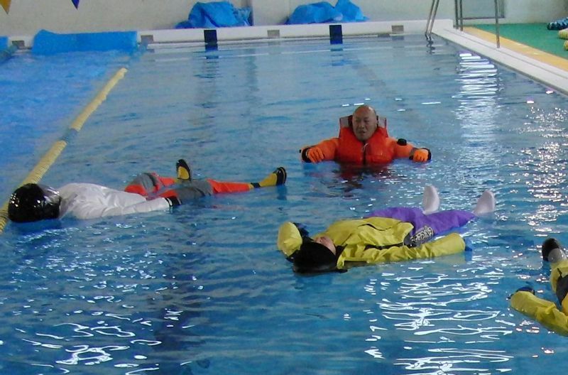 図4 水難学会の冷水実験での背浮きの様子。厚着している分だけ浮きやすく、体の大部分が水面上に出る。立っている男性が着用しているのが、冷水中の水難救助用ドライスーツ（筆者撮影）