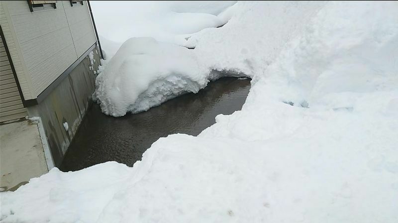 図7 落雪式住宅の軒下に流れている井戸水。屋根から落ちてきた雪を次々と融かす。水深がないので水難事故の心配がない（筆者撮影）
