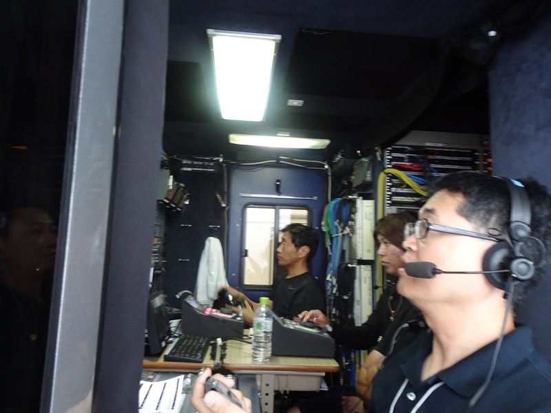 中継車の狭いブースで、編集しながら放送する離れ業に挑む荻山氏と南海放送チーム