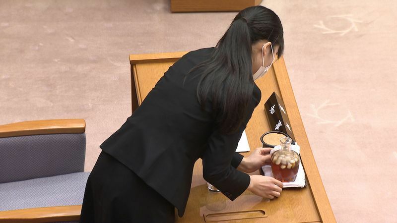 議会で知事の水を用意する女性もパズルのピースの一つだ　（C）石川テレビ放送 