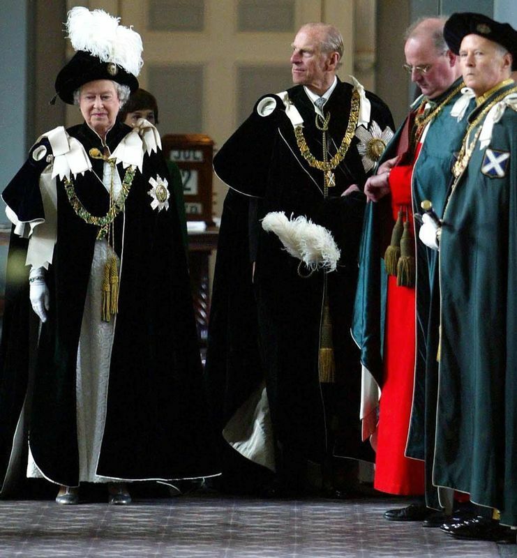 あざみ勲章を身につけたエリザベス女王（とフィリップ王配か）。マントに青地に白いクロスのスコットランド旗が見える。右から二番目の男性の緋色の衣はカトリックを連想させる。