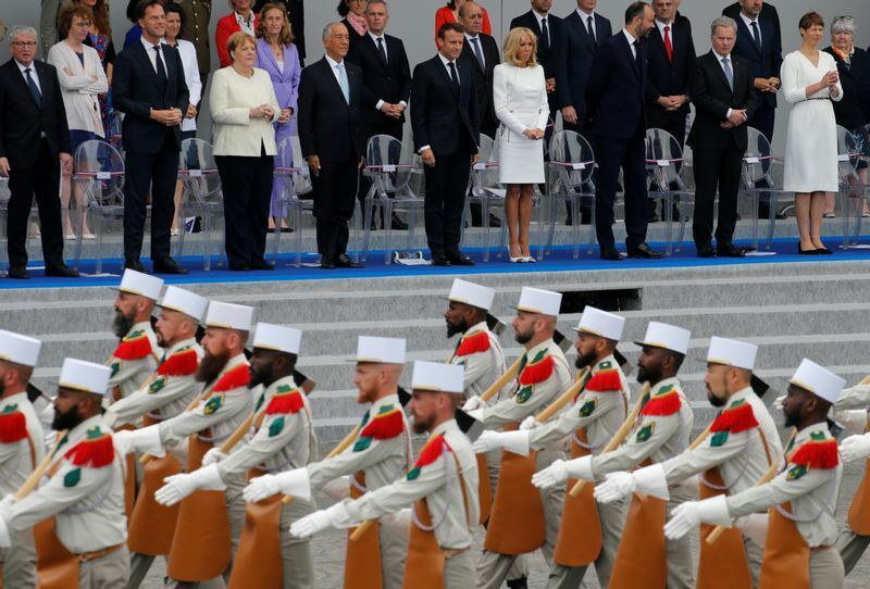 ７月１４日の革命記念日（パリ祭）で、シャンゼリゼ通りの恒例のパレード。手前は正装した外人部隊の人々。向こうにマクロン大統領夫妻や、招待された外国首脳が並ぶ。２０１９年。