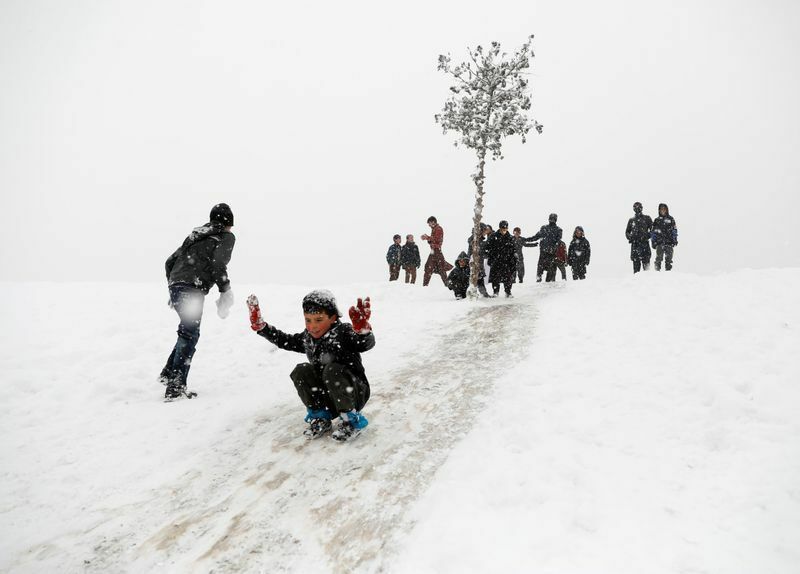 アフガニスタンの冬。2020年冬のひどい嵐が襲った。1月6日カブールで、雪の積もった斜面を滑り降りて遊ぶ少年たち。
